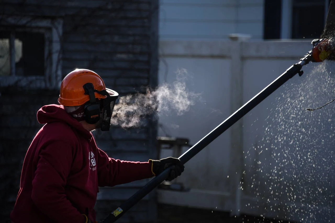 A helmeted worker handles a long tool while their breath catches the light.