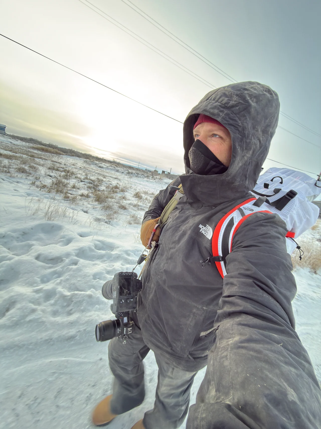 Josh Walker stands in a snow-covered landscape wearing a hood and camera harness.