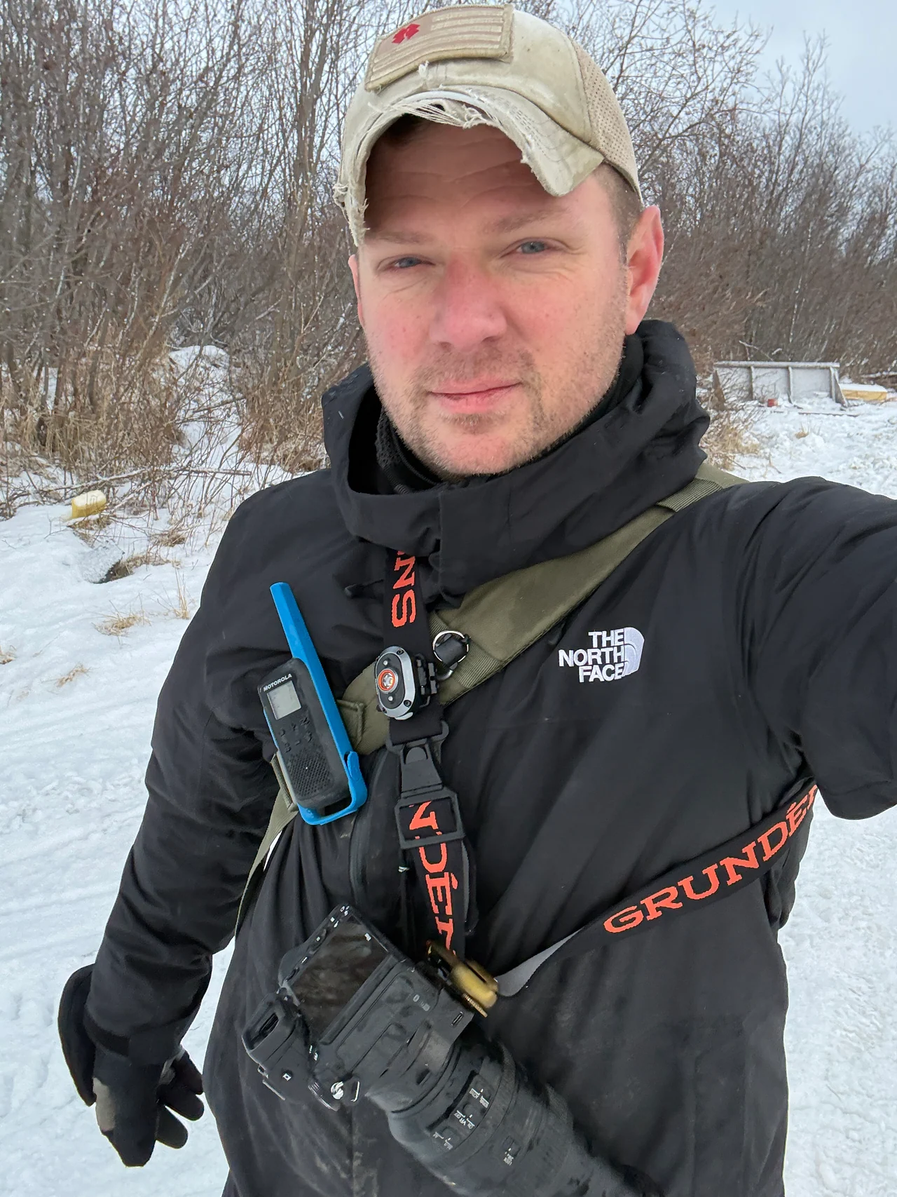Josh Walker stands in snowy woodland wearing a cap and camera harness.